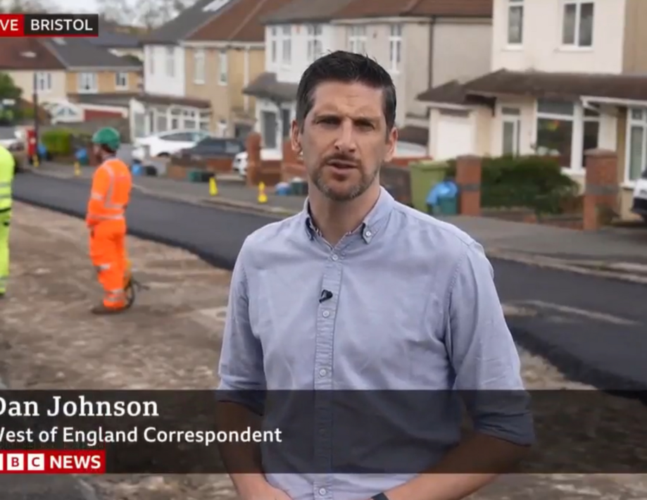 BBC reporter standing on a road that is being repaired